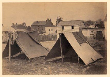 Two small tents, with wood frame buildings in the background LCCN2007675689
