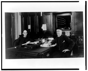 Two Treasury Department employees seated at desk in office LCCN00649577