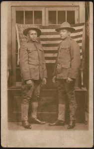 Two unidentified African American soldiers in uniforms and campaign hats standing in front of American flag LCCN2017648675