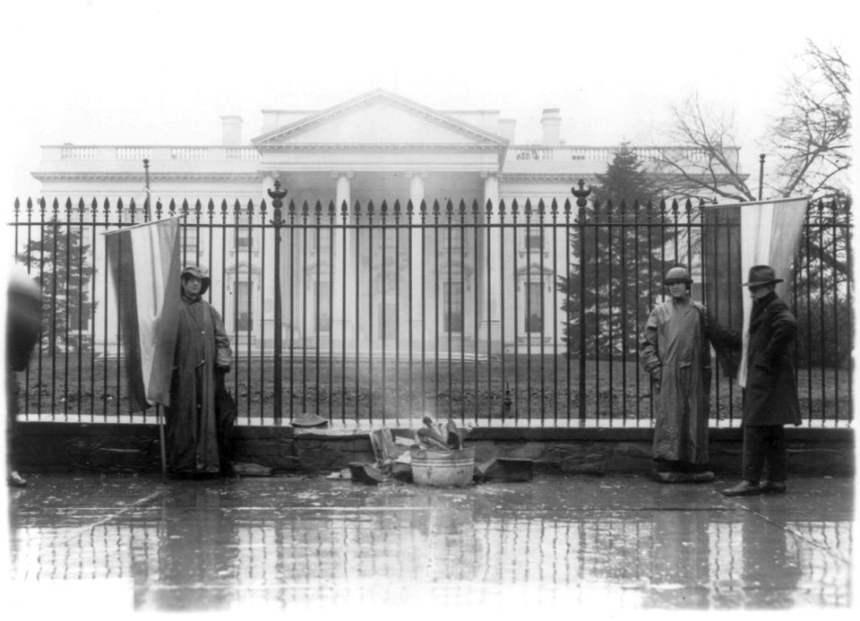 Two suffragettes and bonfire at front gate, White House, Washington, D.C. LCCN2001706175
