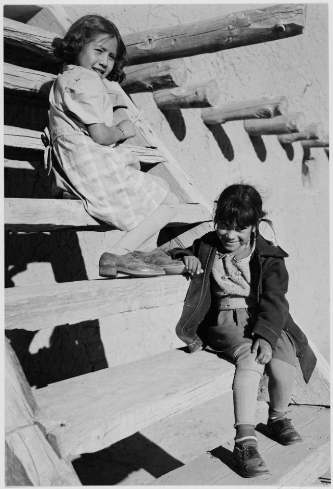 Two young girls sitting on steps. At San Ildefonso Pueblo, New Mexico, 1942. (vertical orientation), 1942 - NARA - 519980