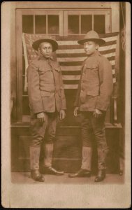 Two unidentified African American soldiers in uniforms and campaign hats standing in front of American flag LCCN2017648675