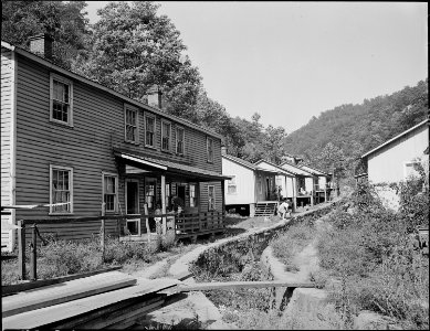 Typical housing, notice the small girl throwing garbage into stream. Panther Red Ash Coal Corporation, Douglas Mine... - NARA - 540986