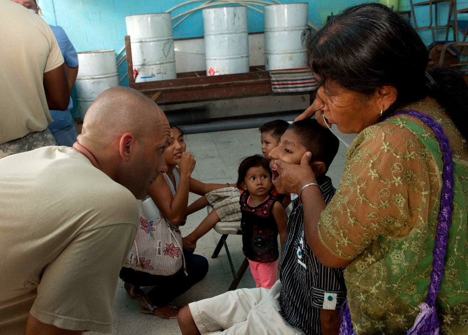 U.S. Army Maj. Michael Mansell, left foreground, attached to Southern Region Dental Command, tends to Guatemalan patients at a medical civic action project (MEDCAP) in Puerto Barrios, Guatemala, Aug. 23, 2014 140823-N-QY430-441