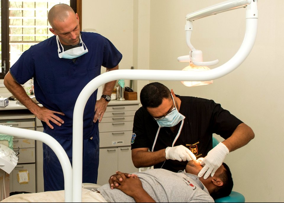 U.S. Army Maj. Michael Mansell, with Southern Region Dental Command, and Dr. Sergio Juarez perform a dental procedure during Southern Partnership Station (SPS) 2014 in Puerto Barrios, Guatemala, Aug. 12, 2014 140812-N-QY430-010