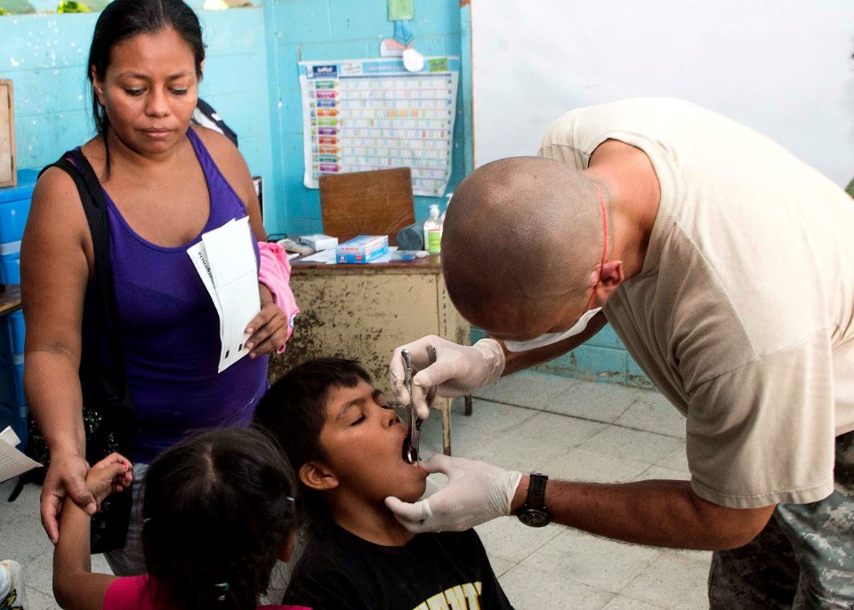 U.S. Army Maj. Michael Mansell, right, attached to Southern Region Dental Command, tends to Guatemalan patients at a medical civic action project (MEDCAP) in Puerto Barrios, Guatemala, Aug. 23, 2014, during 140823-N-QY430-433