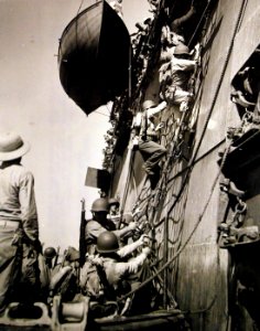 U.S. Marines climb down the rope nets of Army transport into landing boat, WWII (26430967705)