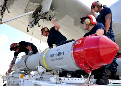 U.S. Navy aviation ordnancemen assigned to Patrol Squadron (VP) 47 prepare to load an AGM-84D Harpoon missile onto the wing of a P-3C Orion