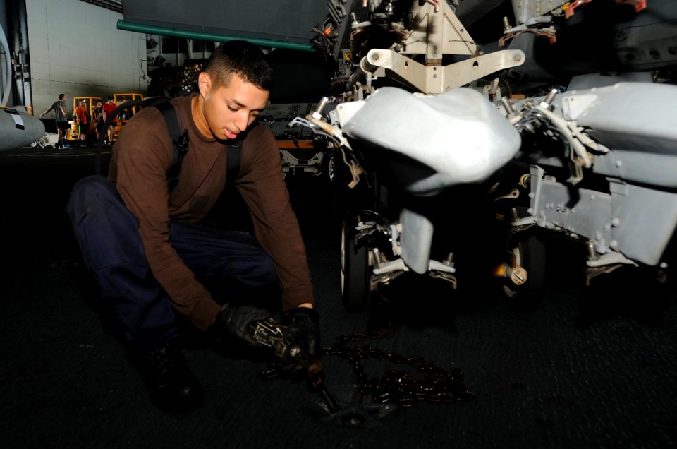 U.S. Navy Airman Elijah Villescas secures an F-A-18F Super Hornet aircraft assigned to Strike Fighter Squadron (VFA) 213 aboard the aircraft carrier USS George H.W. Bush (CVN 77) in the Persian Gulf July 1 140701-N-MU440-049