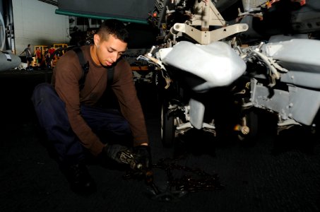 U.S. Navy Airman Elijah Villescas secures an F-A-18F Super Hornet aircraft assigned to Strike Fighter Squadron (VFA) 213 aboard the aircraft carrier USS George H.W. Bush (CVN 77) in the Persian Gulf July 1 140701-N-MU440-049