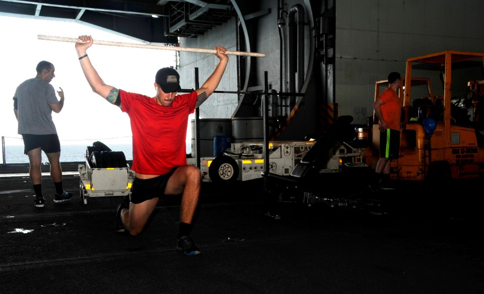 U.S. Naval Aircrewman (Tactical Helicopter) 2nd Class Matt Ballard performs lunges in the hangar bay aboard the aircraft carrier USS George H.W. Bush (CVN 77) in the Persian Gulf July 1, 2014 140701-N-MU440-009
