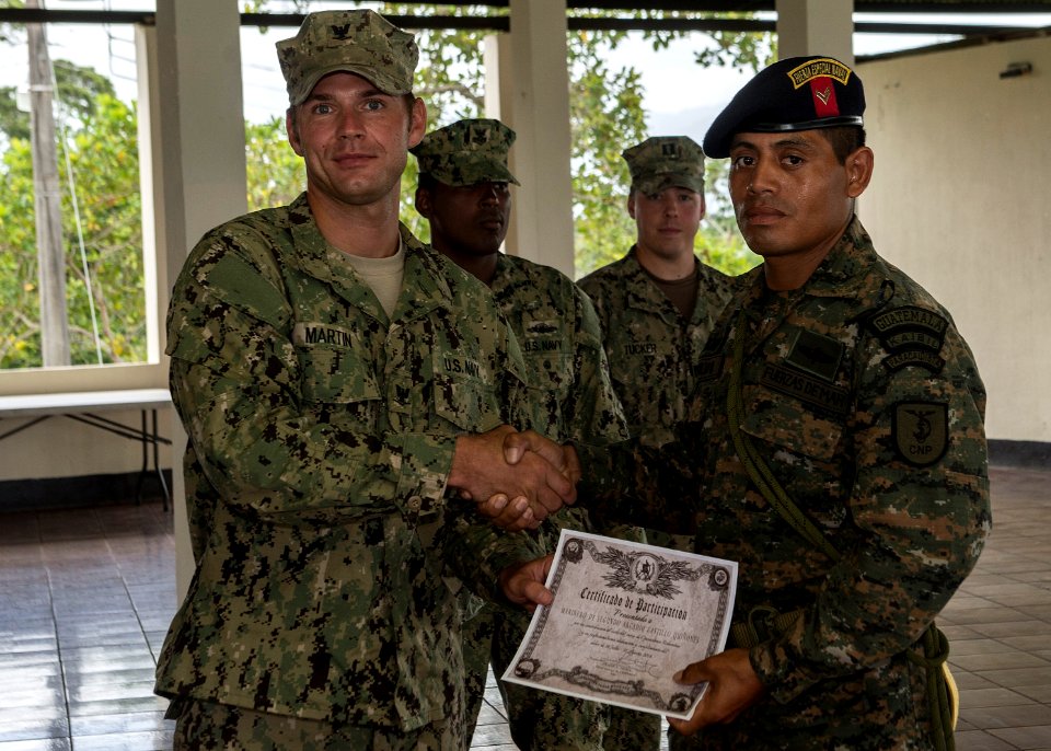U.S. Navy Boatswain's Mate 3rd Class Zach Martin, left, attached to Coastal Riverine Squadron (CORIVRON) 2, gives a certificate to a Guatemalan service member as part of their closing ceremony in Puerto Barrios 140821-N-QY430-044