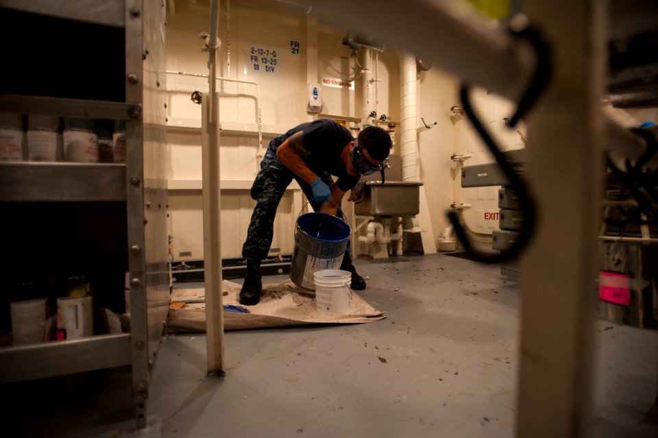 U.S. Navy Aviation Support Equipment Technician Airman David Perez pours paint from a 5-gallon bucket into a smaller container aboard the amphibious assault ship USS America (LHA 6) Sept 140905-N-MZ309-063