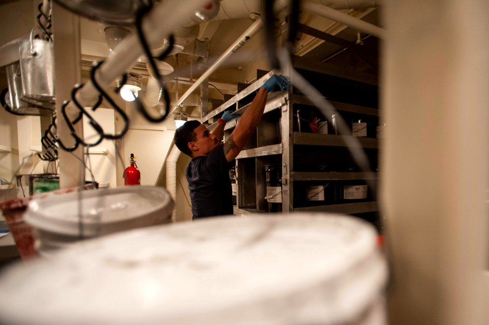 U.S. Navy Aviation Support Equipment Technician Airman David Perez secures shelving in the paint locker aboard the amphibious assault ship USS America (LHA 6) Sept 140905-N-MZ309-038