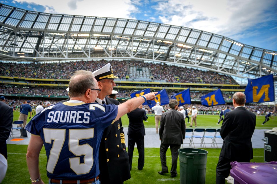U.S. Navy Adm. Jonathan Greenert, foreground, second from left, the chief of Naval operations, watches from the sidelines with a U.S. Naval Academy alumnus as the Midshipmen run onto the football field to play 120901-N-WL435-490
