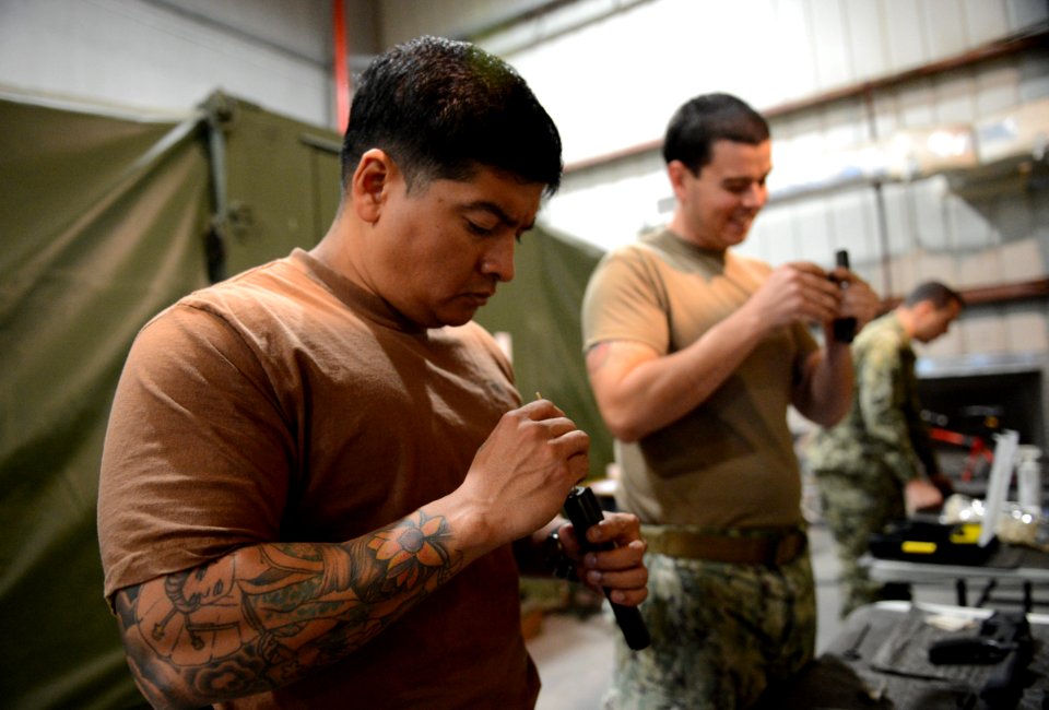 U.S. Navy Boatswain's Mate 1st Class Eddie Montalvo, left, and Mineman 1st Class Thomas Harrell, both assigned to Commander, Task Force (CTF) 56, clean M4 carbine bolt assemblies during weapons training at Naval 140212-N-OU681-157