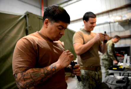 U.S. Navy Boatswain's Mate 1st Class Eddie Montalvo, left, and Mineman 1st Class Thomas Harrell, both assigned to Commander, Task Force (CTF) 56, clean M4 carbine bolt assemblies during weapons training at Naval 140212-N-OU681-157
