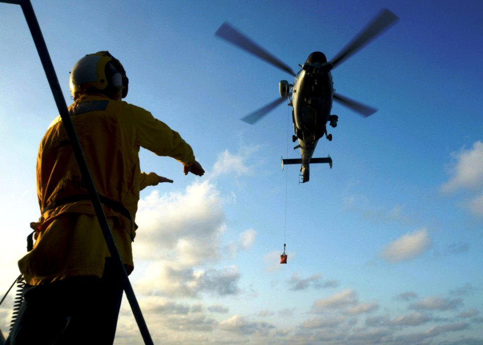 U.S. Navy Boatswain's Mate 2nd Class Chase Pope signals to an Israeli navy AS565 Panther helicopter assigned to the Israeli navy corvette INS Eilat (501) during a vertical replenishment with the guided missile 140409-N-CH661-094