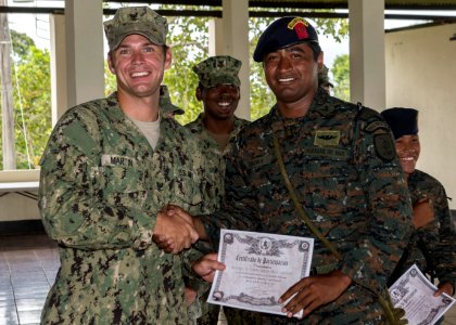 U.S. Navy Boatswain's Mate 3rd Class Zach Martin, left, attached to Coastal Riverine Squadron (CORIVRON) 2, gives a certificate to a Guatemalan service member as part of their closing ceremony in Puerto Barrios 140821-N-QY430-081