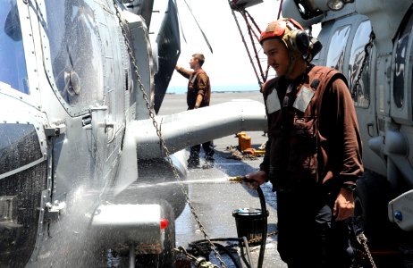 U.S. Navy Aviation Structural Mechanic Airman Fernando Castillo washes an MH-60R Seahawk helicopter assigned to Helicopter Maritime Strike Squadron (HSM) 70 aboard the aircraft carrier USS George H.W. Bush (CVN 140626-N-MU440-035