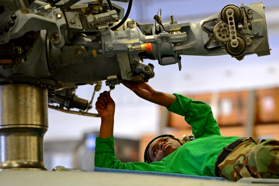U.S. Navy Aviation Machinist's Mate 3rd Class Jhennel Myers, assigned to Helicopter Sea Combat Squadron (HSC) 25, conducts maintenance on an MH-60S Seahawk helicopter in the hangar bay of the amphibious assault 140317-N-BJ178-041
