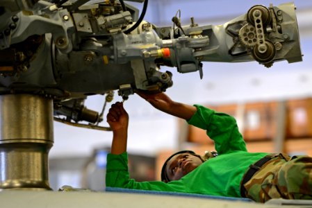U.S. Navy Aviation Machinist's Mate 3rd Class Jhennel Myers, assigned to Helicopter Sea Combat Squadron (HSC) 25, conducts maintenance on an MH-60S Seahawk helicopter in the hangar bay of the amphibious assault 140317-N-BJ178-041
