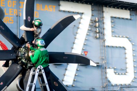 U.S. Navy Aviation Machinist's Mate 3rd Class Clinton Walker, top, and Aviation Machinist's Mate Airman Joseph Soto, both assigned to Carrier Airborne Early Warning Squadron (VAW) 126, perform maintenance on an 140307-N-ZG705-335