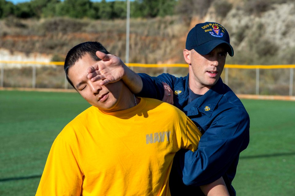 U.S. Navy Chief Fire Controlman Jason Rhodes, right, and Information Systems Technician 2nd Class Yongze Liu demonstrate how to defend against and subdue an attacker to Sailors assigned to the guided missile 131122-N-VC236-013