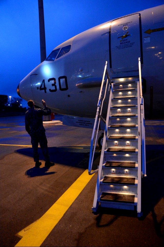 U.S. Navy Aviation Machinist's Mate 3rd Class Justin Kaiser, assigned to Patrol Squadron (VP) 16, uses a flashlight to check the structural integrity of a P-8A Poseidon aircraft before a mission to assist in sear 140401-N-VD564-044