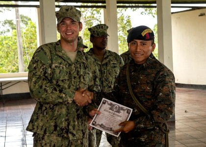 U.S. Navy Boatswain's Mate 3rd Class Zach Martin, left, attached to Coastal Riverine Squadron (CORIVRON) 2, gives a certificate to a Guatemalan service member as part of their closing ceremony in Puerto Barrios 140821-N-QY430-042