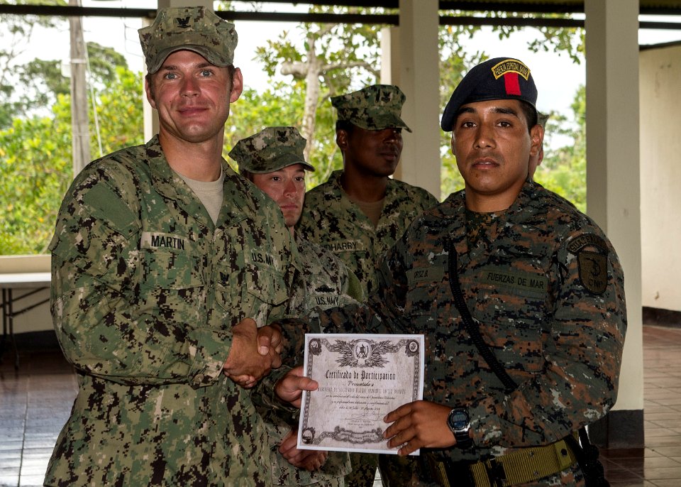 U.S. Navy Boatswain's Mate 3rd Class Zach Martin, attached to Coastal Riverine Squadron (CORIVRON) 2, gives a certificate to a Guatemalan service member as part of their closing ceremony in Puerto Barrios 140821-N-QY430-048