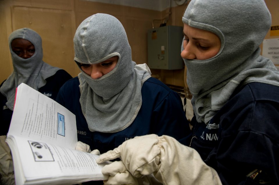U.S. Navy Damage Controlman 1st Class Ryanne Clingersmith, right, provides training to Logistics Specialist 2nd Class Estephanie Romero Navarro during a general quarters drill aboard the amphibious assault ship 140906-N-MD297-013