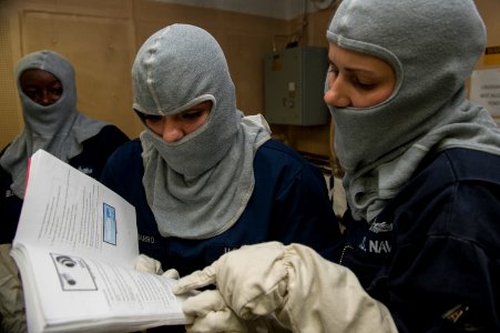U.S. Navy Damage Controlman 1st Class Ryanne Clingersmith, right, provides training to Logistics Specialist 2nd Class Estephanie Romero Navarro during a general quarters drill aboard the amphibious assault ship 140906-N-MD297-013