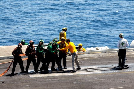 U.S. Navy Chief Aviation Boatswain's Mate (Handling) Shawn Riley, center right, instructs Sailors on proper fire hose handling techniques June 27, 2014, during a general quarters drill on the flight deck of 140627-N-CZ979-049