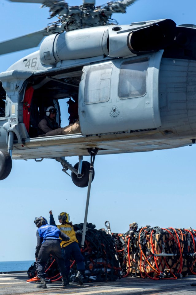 U.S. Navy Boatswain's Mate 3rd Class Damaris Urena, right, and Seaman Isaac Kinder hook cargo to an MH-60R Seahawk helicopter assigned to Helicopter Sea Combat Squadron (HSC) 28 aboard the guided missile cruiser 140409-N-PJ969-171