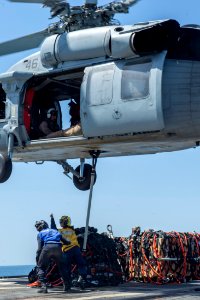 U.S. Navy Boatswain's Mate 3rd Class Damaris Urena, right, and Seaman Isaac Kinder hook cargo to an MH-60R Seahawk helicopter assigned to Helicopter Sea Combat Squadron (HSC) 28 aboard the guided missile cruiser 140409-N-PJ969-171