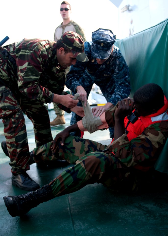 U.S. Navy Chief Hospital Corpsman Amber Smoker, center, an exercise medical lead, assists a Moroccan sailor in providing first aid to a Liberian coast guardsman portraying a casualty during maritime interdiction 140309-N-QY759-168
