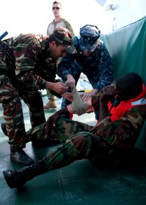 U.S. Navy Chief Hospital Corpsman Amber Smoker, center, an exercise medical lead, assists a Moroccan sailor in providing first aid to a Liberian coast guardsman portraying a casualty during maritime interdiction 140309-N-QY759-168