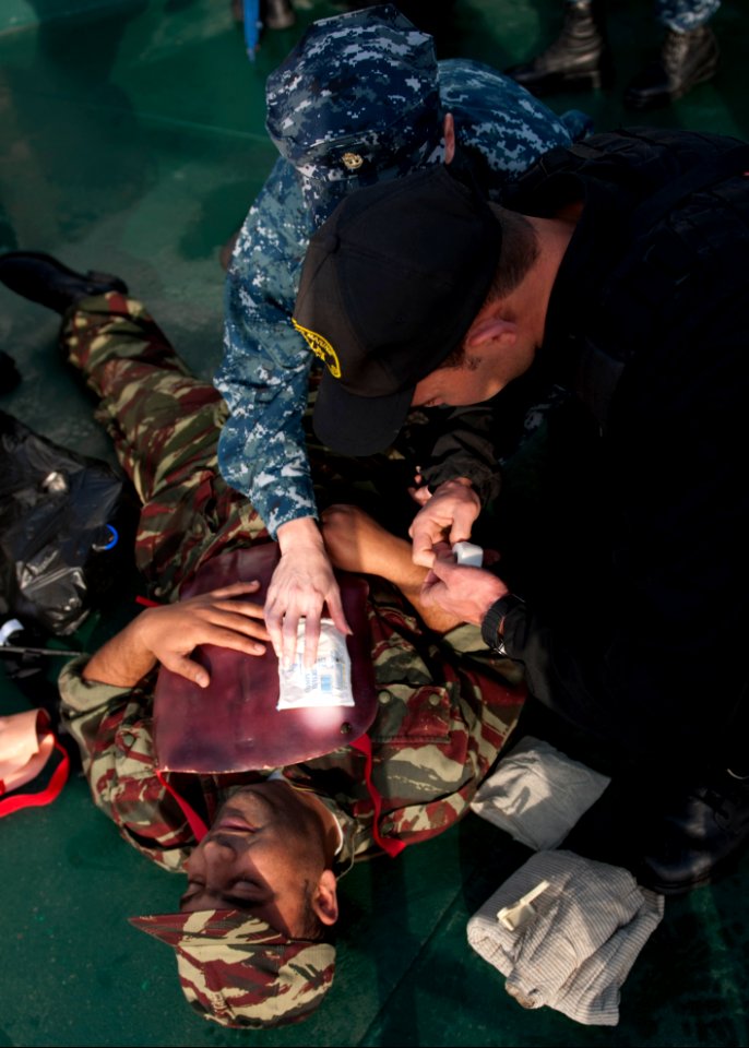 U.S. Navy Chief Hospital Corpsman Amber Smoker, center, an exercise medical lead, assists a Moroccan sailor in providing first aid to a Liberian coast guardsman portraying a casualty during maritime interdiction 140309-N-QY759-099