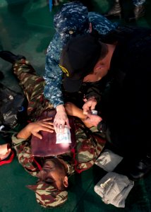 U.S. Navy Chief Hospital Corpsman Amber Smoker, center, an exercise medical lead, assists a Moroccan sailor in providing first aid to a Liberian coast guardsman portraying a casualty during maritime interdiction 140309-N-QY759-099