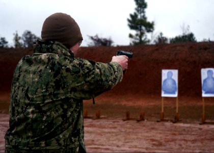 U.S. Navy Hospital Corpsman 1st Class James Spieker, with Naval Mobile Construction Battalion (NMCB) 25, takes aim during Naval Construction Group 2's M9 pistol qualification course in Woolmarket, Miss 140211-N-JP566-066