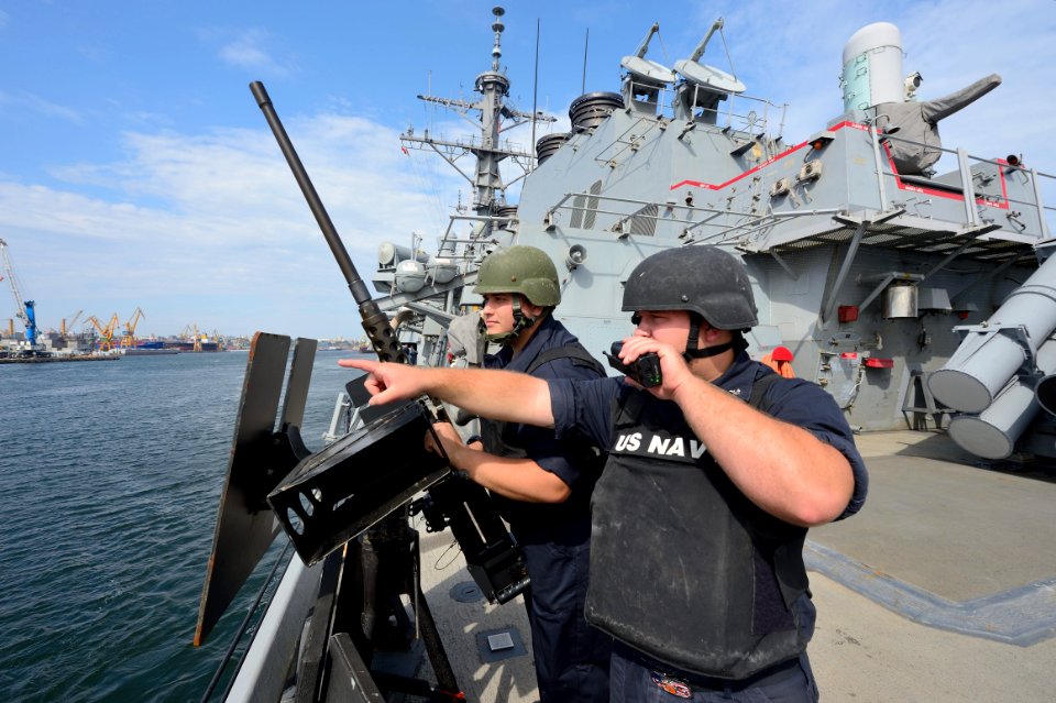 U.S. Navy Gunner's Mate 3rd Class David Lewis, right, radios in a surface contact while on watch aboard the guided missile destroyer USS Ross (DDG 71) as the ship departs Constanta, Romania, Sept 140907-N-IY142-201