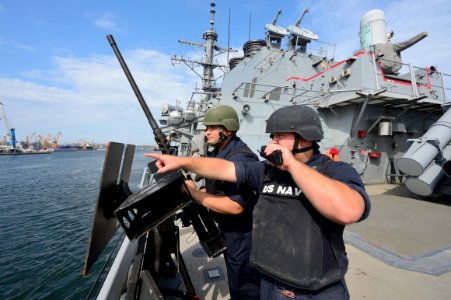 U.S. Navy Gunner's Mate 3rd Class David Lewis, right, radios in a surface contact while on watch aboard the guided missile destroyer USS Ross (DDG 71) as the ship departs Constanta, Romania, Sept 140907-N-IY142-201