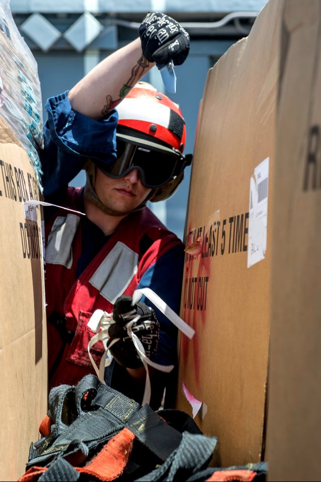 U.S. Navy Culinary Specialist 3rd Class Darron May removes cargo nets during a vertical replenishment aboard the guided missile cruiser USS Philippine Sea (CG 58) in the Arabian Sea April 9, 2014 140409-N-PJ969-128