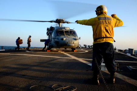 U.S. Navy Boatswain's Mate 1st Class Rolando Rios directs Sailors to approach an MH-60S Seahawk helicopter assigned to Helicopter Sea Combat Squadron (HSC) 26 during Spartan Kopis Dec. 7, 2013, aboard the guided 131207-N-OU681-183