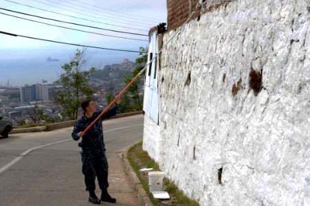 U.S. Navy Boatswain's Mate 3rd Class John Hardy, assigned to the newly commissioned amphibious assault ship USS America (LHA 6), paints an exterior wall at a children's home in Valparaiso, Chile, Aug. 26, 2014 140826-N-MZ309-162