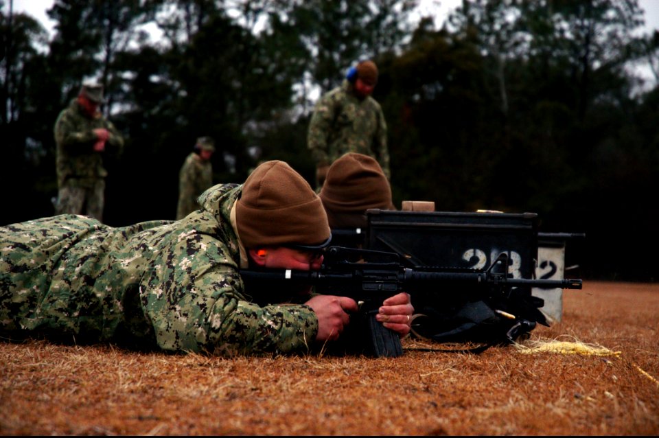U.S. Navy Construction Mechanic 2nd Class Brent Rensink, foreground, with Naval Mobile Construction Battalion (NMCB) 25, fires an M4 carbine during Naval Construction Group 2's M4-M16 qualification course 140211-N-JP566-113