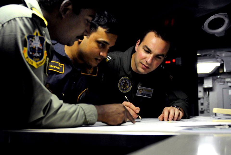 U.S. Navy Lt. Dan Mitzner reviews an exercise scenario in the undersea warfare module in the combat direction center aboard the USS Carl Vinson with Indian Navy liaison officers