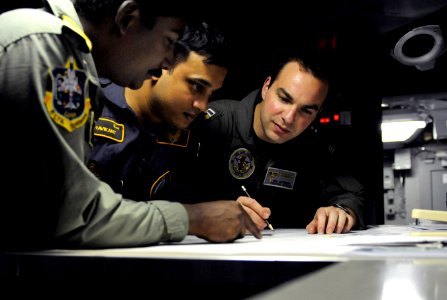 U.S. Navy Lt. Dan Mitzner reviews an exercise scenario in the undersea warfare module in the combat direction center aboard the USS Carl Vinson with Indian Navy liaison officers