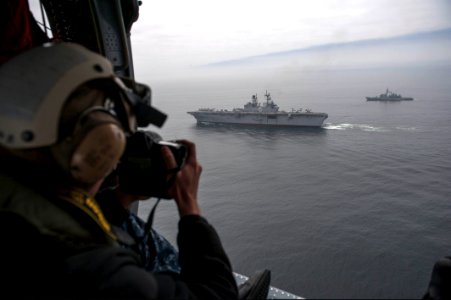 U.S. Navy Mass Communication Specialist 2nd Class Jonathan Colon takes photos of the amphibious assault ship USS America (LHA 6), center, and Peruvian Navy ships as they sail in formation during a passing 140903-N-MZ309-711